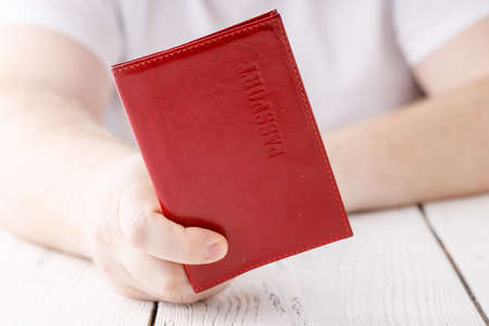 Closeup of hand holding passport on white