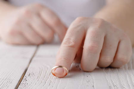 Man removes a gold wedding ring from his finger. Concept of family quarrel, divorce or betrayalの写真素材