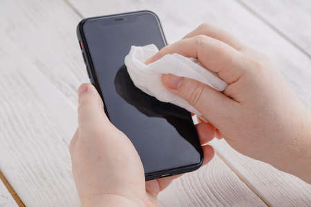 Phone screen disinfecting wipe cleaning removing germs with antibacterial wipes for corona virus COVID-19の写真素材