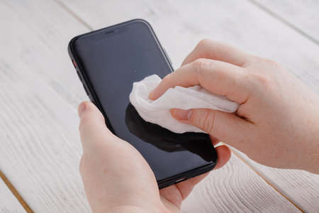 Covid 19 prevention applying alkohol desinfection to mobile phoneの写真素材