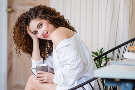 Happy woman relaxing and enjoying stress free weekend at home, calm satisfied girl stretching on couch thinking of pleasant lazy day, dreaming and planning sunday morningの写真素材