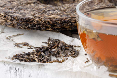 A cup of Chinese tea is next to a large piece of puerの写真素材
