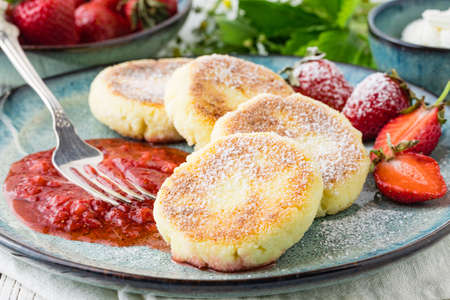 Cottage cheese pancakes (syrniki). Homemade cheesecakes from cottage cheese with sour cream, berries and milk. Traditional Russian dish. Close-upの写真素材