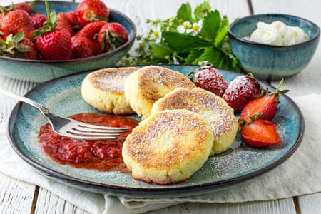Frying homemade Cottage cheese pancakes Russian syrniki with strawberry on  plate. Breakfast timeの写真素材