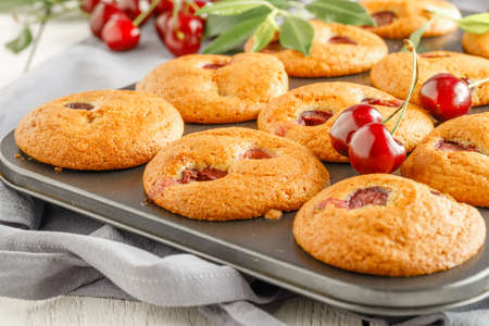 Homemade cherry muffins and fresh cherries on a light background. Delicious dessertの写真素材