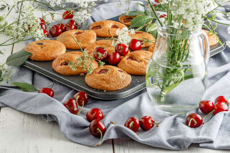 Homemade cherry muffins and fresh cherries on a light background. Delicious dessertの写真素材