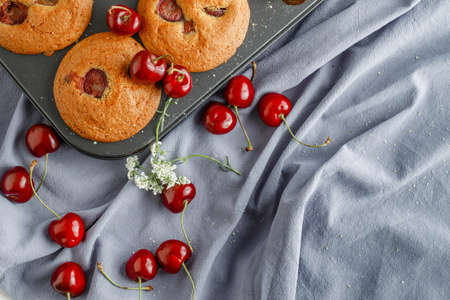 Cherry muffins with the addition of fresh cherries on on a cooling tray, close-up. Delicious dessertの写真素材