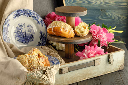 Breakfast with croissants, leaves, flowers composition with retro plates on wooden backgroundの写真素材