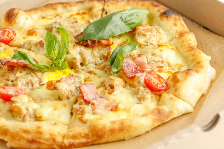 Close up of pizzas with variety of toppings and cheese in cardboard take out boxes with open lid on wooden tableの写真素材