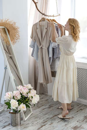 Woman shopping choosing dresses looking in mirror uncertainの写真素材