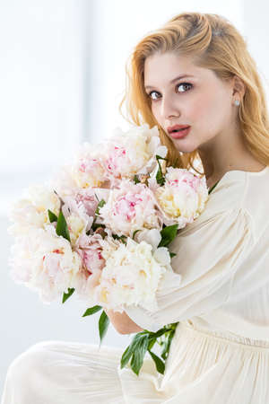 beautiful sensual girl with long blonde hair in dress with a bouquet of pink peonies flowers. Ð¡oncept of feminityの写真素材