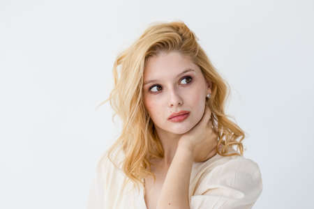 Cheerful lovely girl with amazing smile and romantic hairstyle gladly posing in white room. Portrait of cute young woman with flower in sunny morningの写真素材