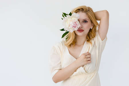 Indoor shot of beautiful girl holding white and rose peonies, winsome woman with big bouquet, enjoying her flowersの写真素材