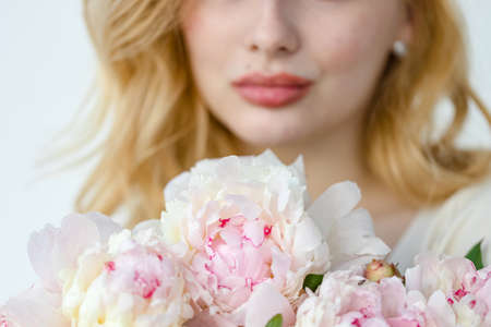Girl with pink peonies bouquet at white wallの写真素材