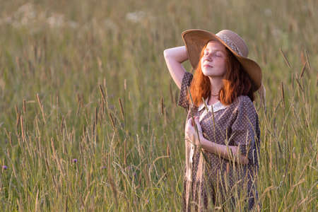 redhead model posing in a meadow at sunsetの写真素材
