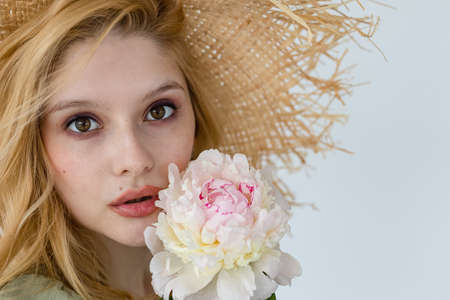 Indoor shot of beautiful girl holding white and rose peonies, winsome woman with big bouquet, enjoying her flowersの写真素材