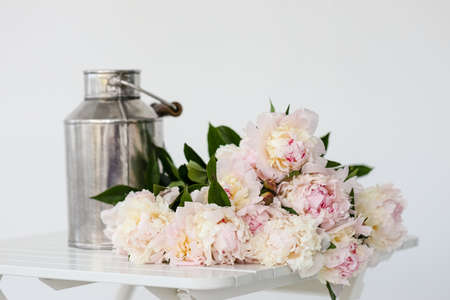 Flowers on a white table near the window. Beautiful peony flower for catalog or online store. Floral shop and delivery concept. Copy spaceの写真素材