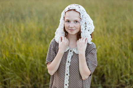 emotional redhead girl playing in the grass on a summer meadow at sunset in an elegant dressの写真素材