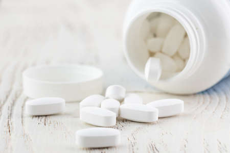 White empty medical jar, scattered tablets in capsulesの写真素材