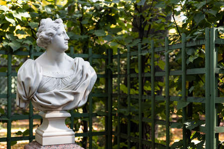 Old park statue of sensual Greek or Italian Renaissance Era woman with flowers in city park went to golden Autumn colors,の写真素材