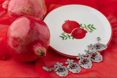 pomegranate fruit with turkish jewelery and open pomegranate on an red, side viewの写真素材