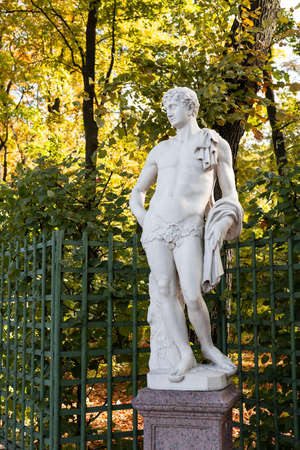 Old park statue of sensual Greek or Italian Renaissance Era woman with flowers in city park went to golden Autumn colors,の写真素材