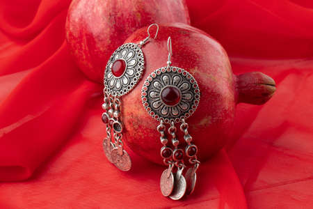 pomegranate fruit with turkish jewelery and open pomegranate on an red, side viewの写真素材