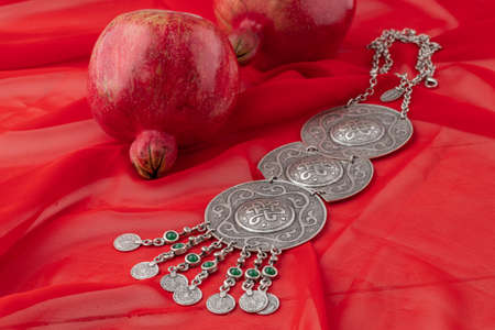pomegranate fruit with turkish jewelery and open pomegranate on an red, side viewの写真素材
