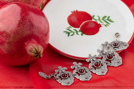 pomegranate fruit with turkish jewelery and open pomegranate on an red, side viewの写真素材