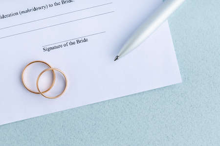 Sign of marriage contract form agreement with a pair of wedding ringsの写真素材