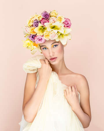 Surprised and happy young blond girl posing in studio, flowers in headの写真素材