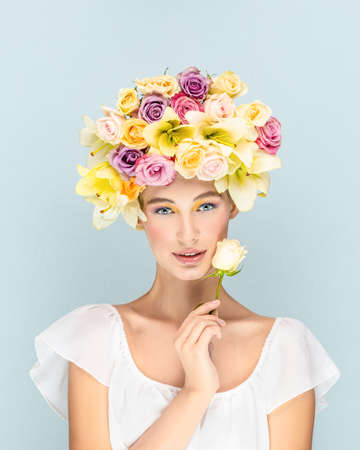 Mysterious young girl looks into the camera lens with flowers in the headの写真素材