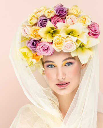 Young beautiful woman with bouquet of flower in head. Art portrait of sexy blonde with colorful flowers. Professional art makeup. Pretty pink background. Happy conceptの写真素材