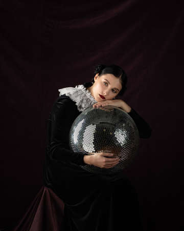 Studio portrait of young woman with object in hands on black backgroundの写真素材