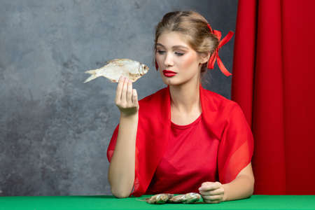 young girl in the studio with dried fish. Unusual footageの写真素材