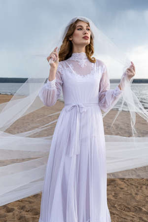 Happy young girl in a white dress on the sandy shore. Thunder skyの写真素材