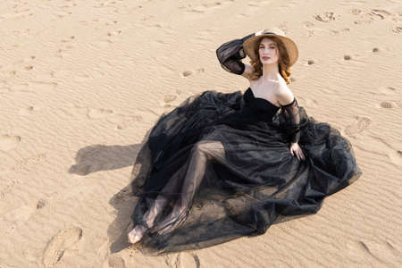 Happy young girl in a straw hat and in a black dress on the bank of the river. Thunder skyの写真素材