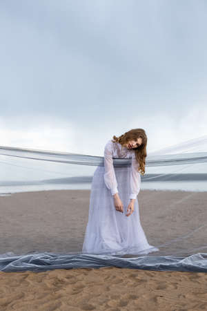 Happy young girl in a white dress on the sandy shore. Thunder skyの写真素材