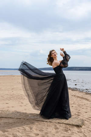 young girl in a black dress by the riverの写真素材