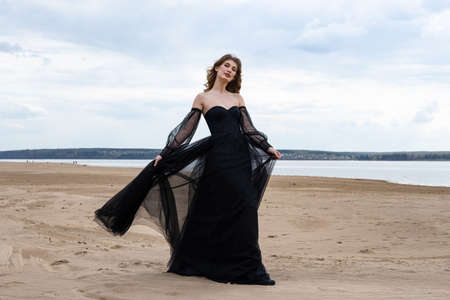 Happy young girl in black dress on the river bankの写真素材