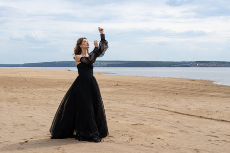 Happy young girl in black dress on the river bankの写真素材