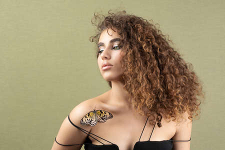Fashion beauty model with butterfly on face and color professional makeup. SPA, wellness, make-up and skincare concept.の写真素材