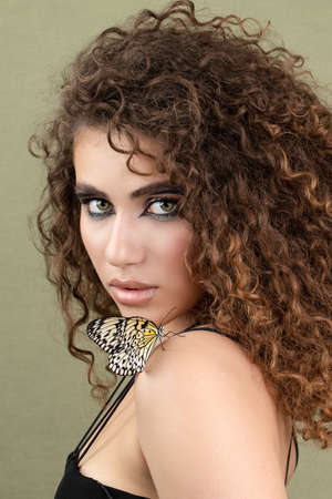 Fashion beauty model with butterfly on face and color professional makeup. SPA, wellness, make-up and skincare concept.の写真素材