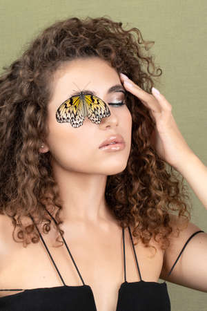 Close-up portrait of a young girl with the makeup. Creative makeup, lively butterfly on the model's face.の写真素材