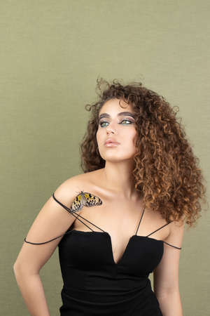 Beautiful young woman with perfect skin and bright yellow make up posing with butterfly on her face.の写真素材