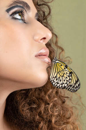 Close-up portrait of a young girl with the makeup. Creative makeup, lively butterfly on the model's face.の写真素材