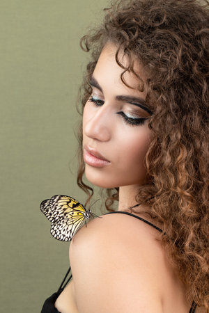Beauty model girl posing, fashion make up with butterfly. Art design colorful make up with golden butterfliesの写真素材