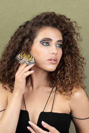Beauty model girl posing, fashion make up with butterfly. Art design colorful make up with golden butterfliesの写真素材