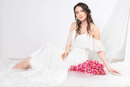 Sexy woman with flowers pink tulips in hands on a light backgroundの写真素材
