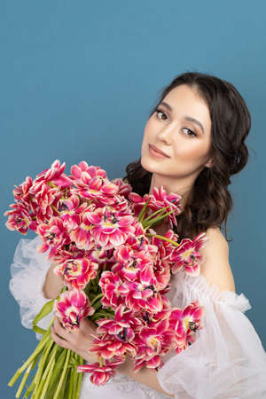 Beautiful young girl holding pink flower buds in her hands.の写真素材
